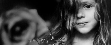 Foto blanco y negro retrato de un niña con una rosa en el fondo, obra de Letizia Battaglia.