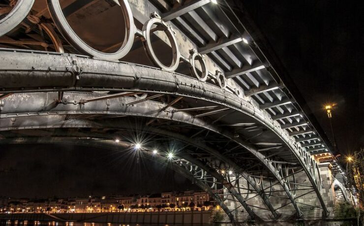 Imagen nocturna del Puente de Triana antes del amanecer, visto desde la orilla izquiera del Guadalquivir