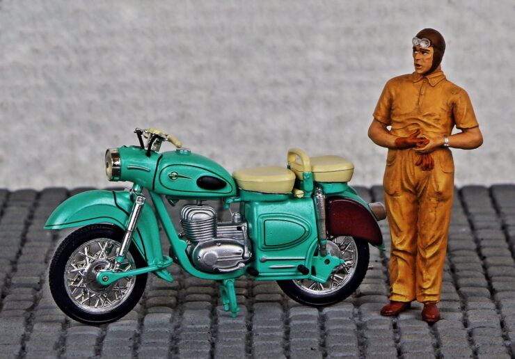 Modelo de la motocicleta MZ ES 250 con el muñeco de u conductor al lado. Portada de homenaje poético a las motocicletas