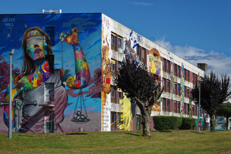 Un graffiti que cubre el lado entero de un bloque y que representa la deosa justicia bendada