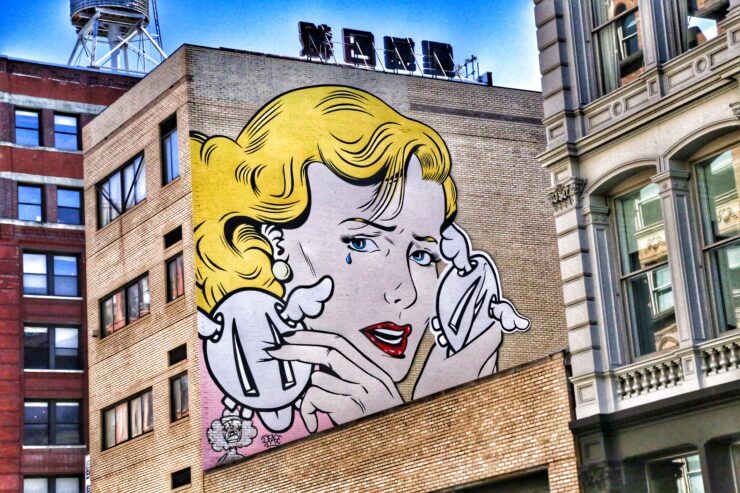 En la parde de un bloque entre altos edificios un grafiti estilo comic de una mujer que llora