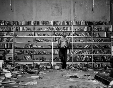 El protagonista de la foto es un lector en el medio de una habitación llenas de libros y medio en ruinas