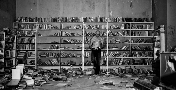El protagonista de la foto es un lector en el medio de una habitación llenas de libros y medio en ruinas